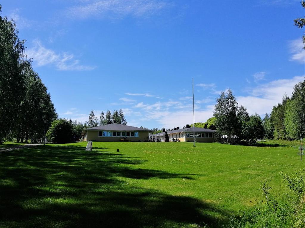 a large grass field with a house in the background at Loma Luonnonlapsi in Sotkamo