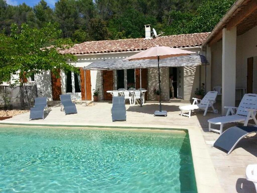una piscina con sillas, una mesa y una sombrilla en Villa de 4 chambres avec piscine privee et jardin clos a Le Beaucet, en Le Beaucet