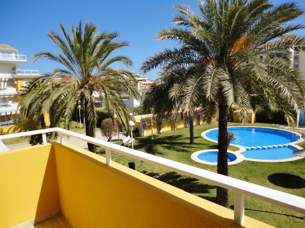 a balcony with palm trees and a swimming pool at Comfortable Apartment in Dénia + Pool in Denia
