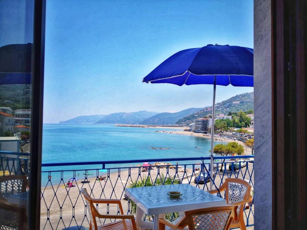 a table with an umbrella on a balcony with a beach at La Casa di Aurelio in Capo dʼOrlando