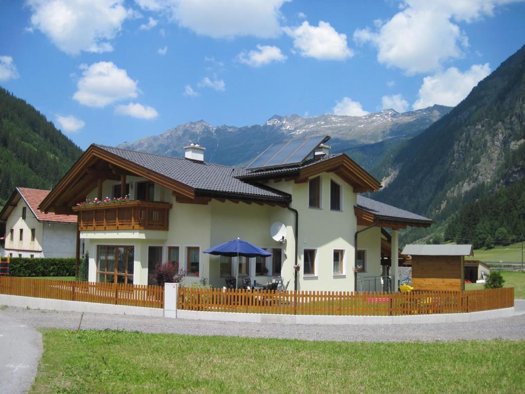 une maison avec une clôture en face d'une montagne dans l'établissement Apart Larcher, à Kaunertal