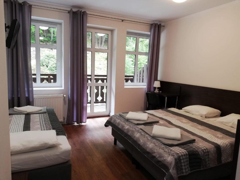 a hotel room with two beds and windows at Słoneczna in Miedzygorze