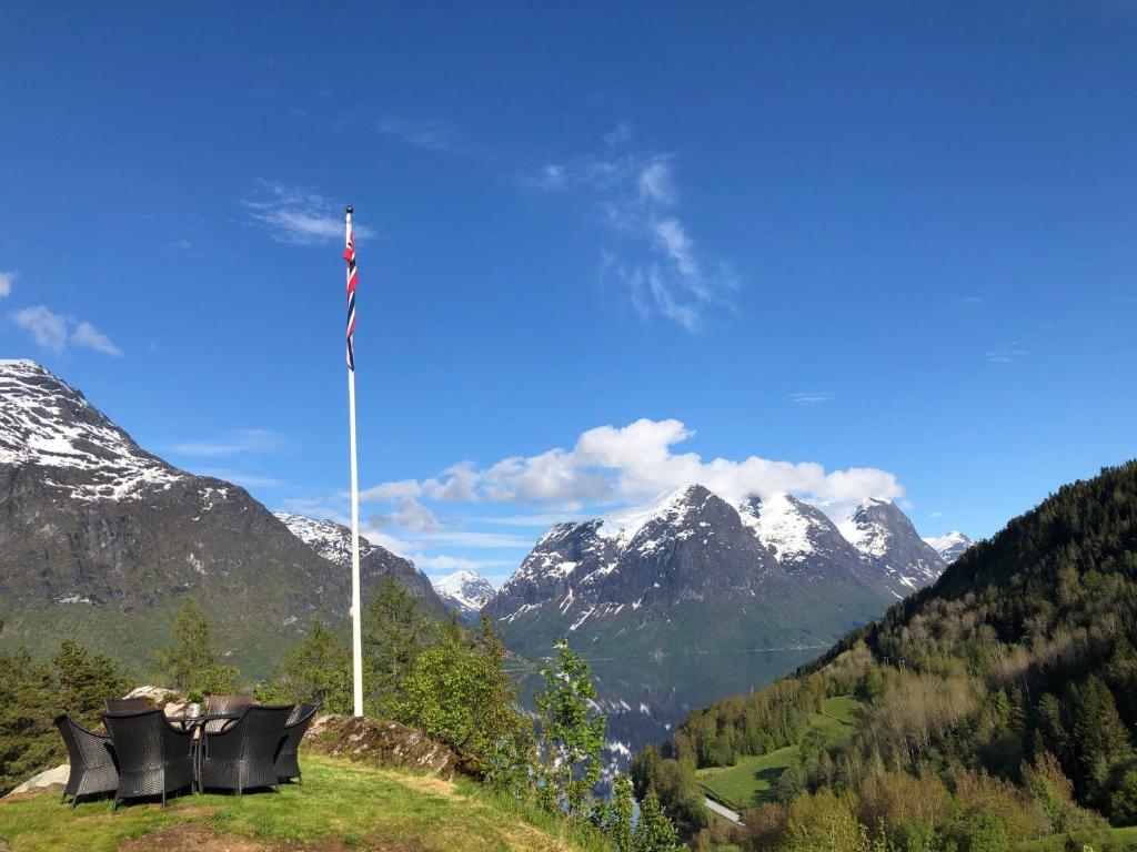 a flag pole with chairs on a hill with mountains at Tunold Gård - Freden in Stryn