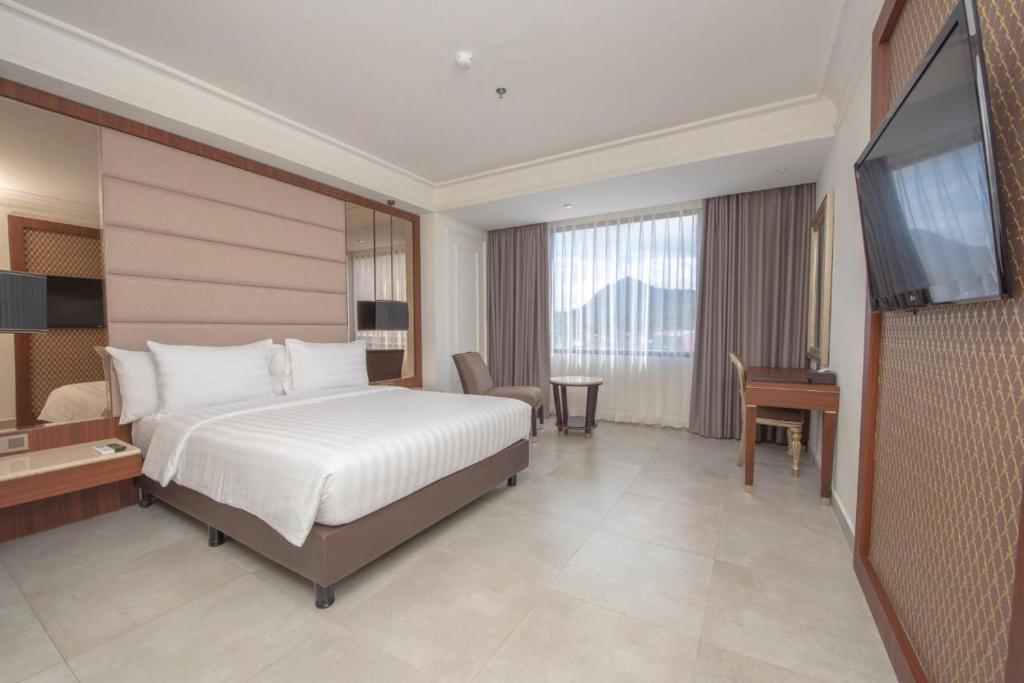 um quarto de hotel com uma cama e uma televisão de ecrã plano em Mahkota Hotel Singkawang em Singkawang