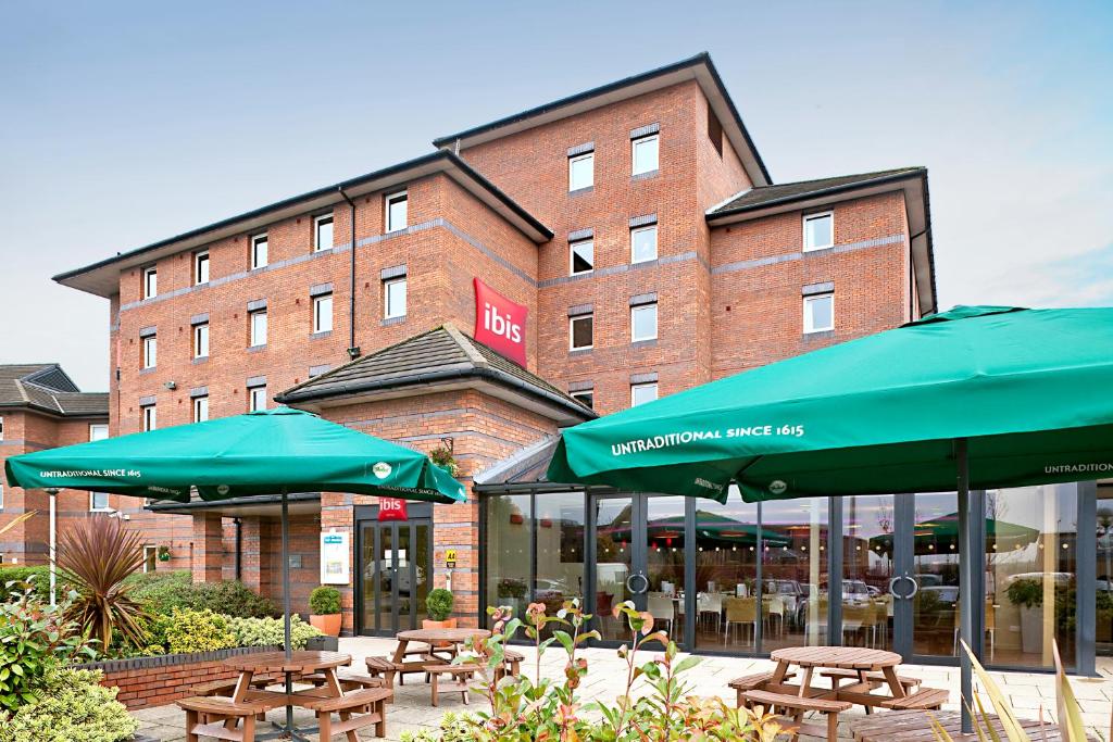 a restaurant with tables and umbrellas in front of a building at ibis Liverpool Centre Albert Dock – Liverpool One in Liverpool