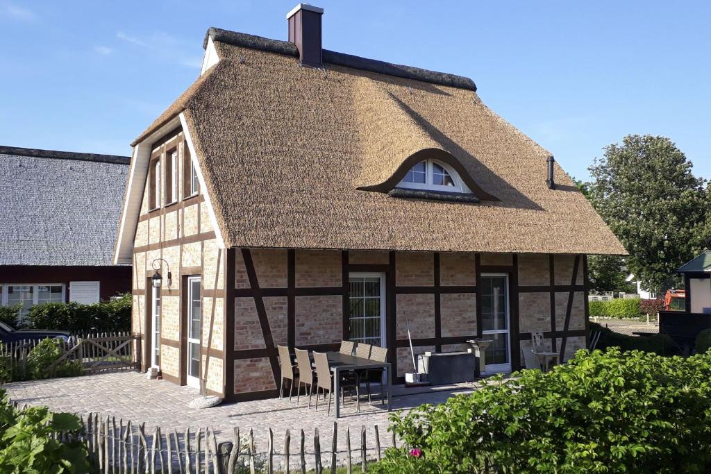 a house with a thatched roof with a table and chairs at Ferienhaus Min Hüsung Haus - Terrasse, Garten in Gager