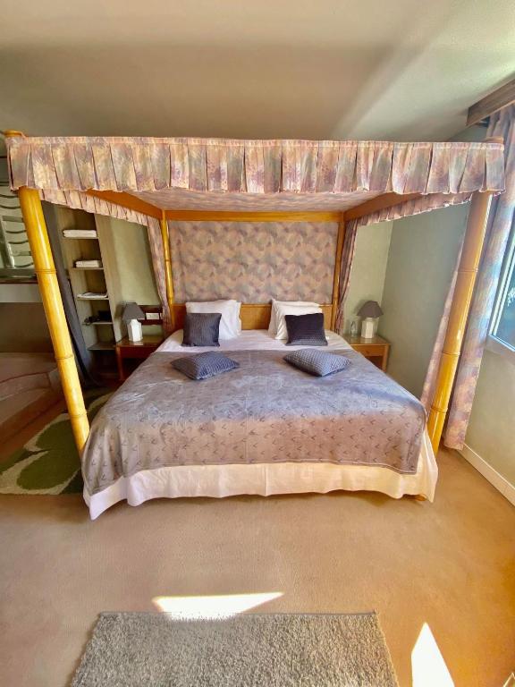 une chambre avec un grand lit à baldaquin dans l'établissement Le Relais Du Haras - Deauville, à Touques