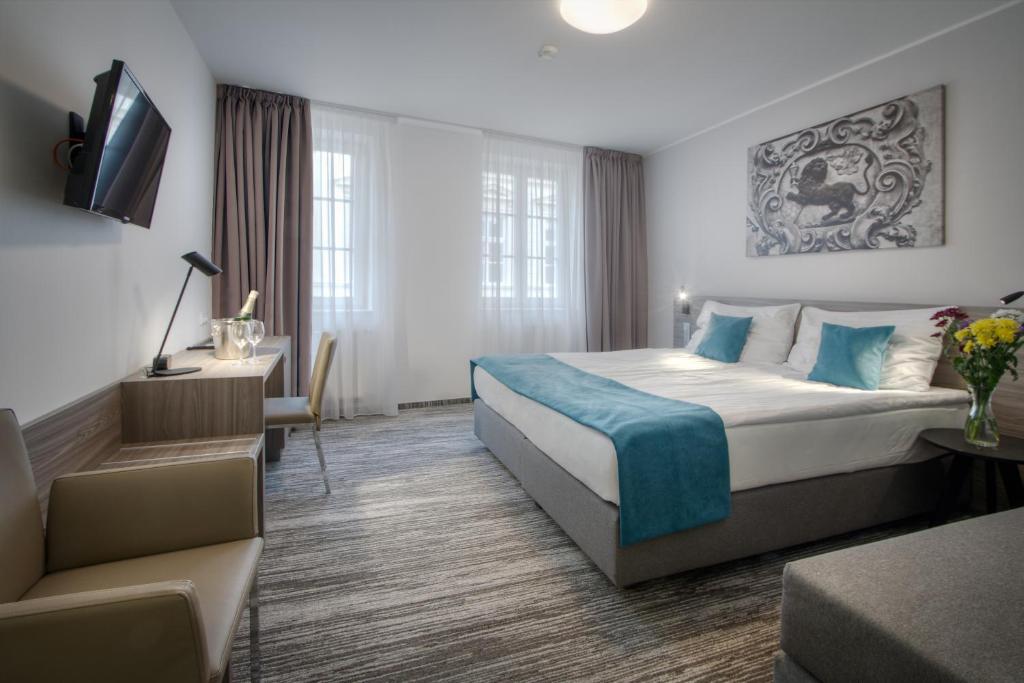 a hotel room with a large bed and a desk at Hotel Páv in Prague