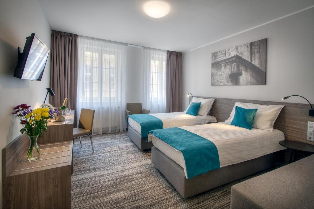a hotel room with two beds and a tv at Hotel Páv in Prague