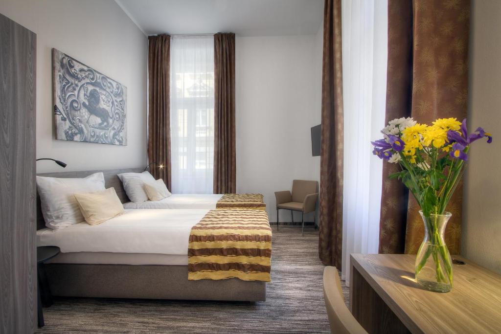 a hotel room with a bed and a vase of flowers at Hotel Páv in Prague