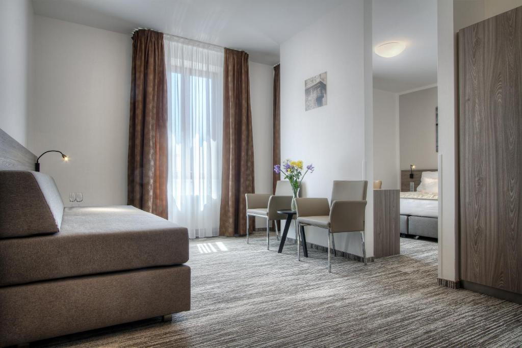 a hotel room with a couch and a table and a bed at Hotel Páv in Prague