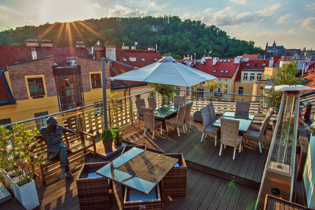 Ein Mann, der mit einem Tisch und einem Regenschirm auf einem Deck sitzt. in der Unterkunft Hotel Julian in Prag