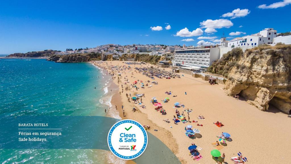 
a beach filled with lots of beach chairs and umbrellas at Hotel Sol e Mar Albufeira in Albufeira
