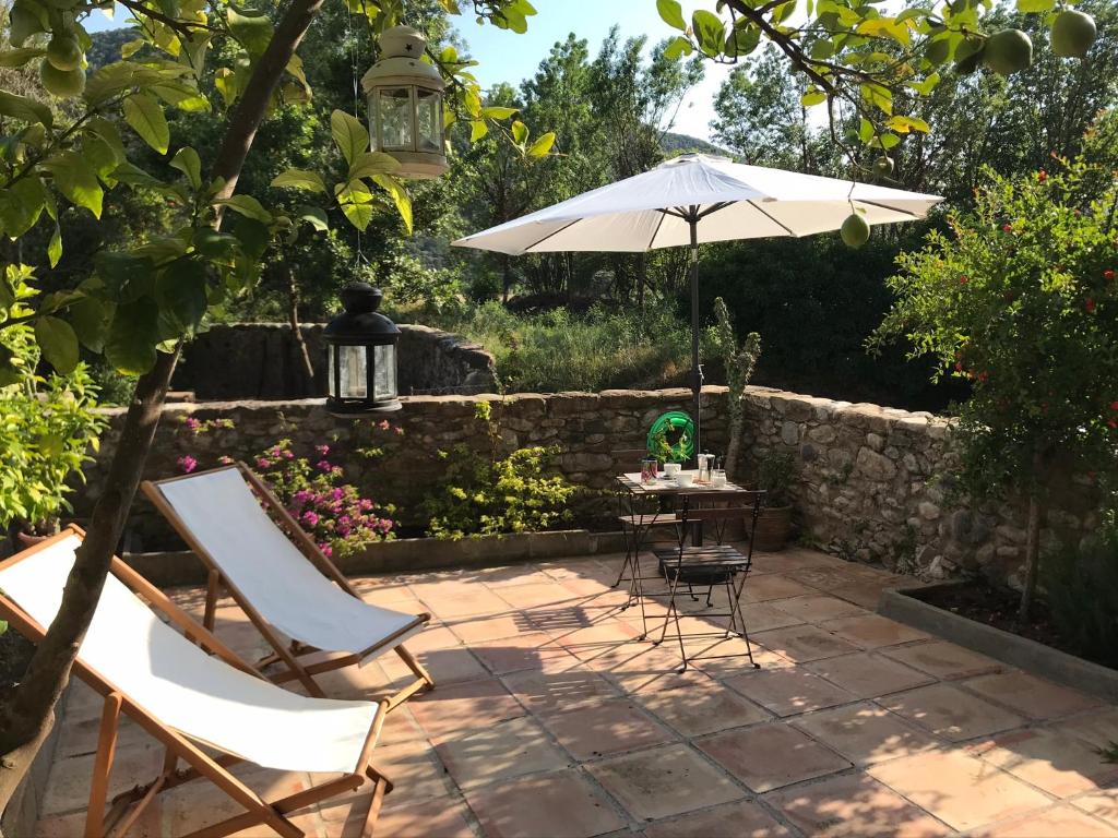 une terrasse avec un parasol, des chaises et une table dans l'établissement Can Giribets, à Argelaguer