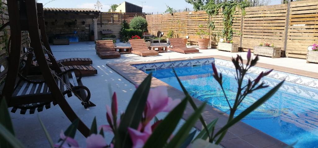 un patio trasero con una piscina con sillas y una valla en Cal Roig Hotel Rural en Vilafranca del Penedès