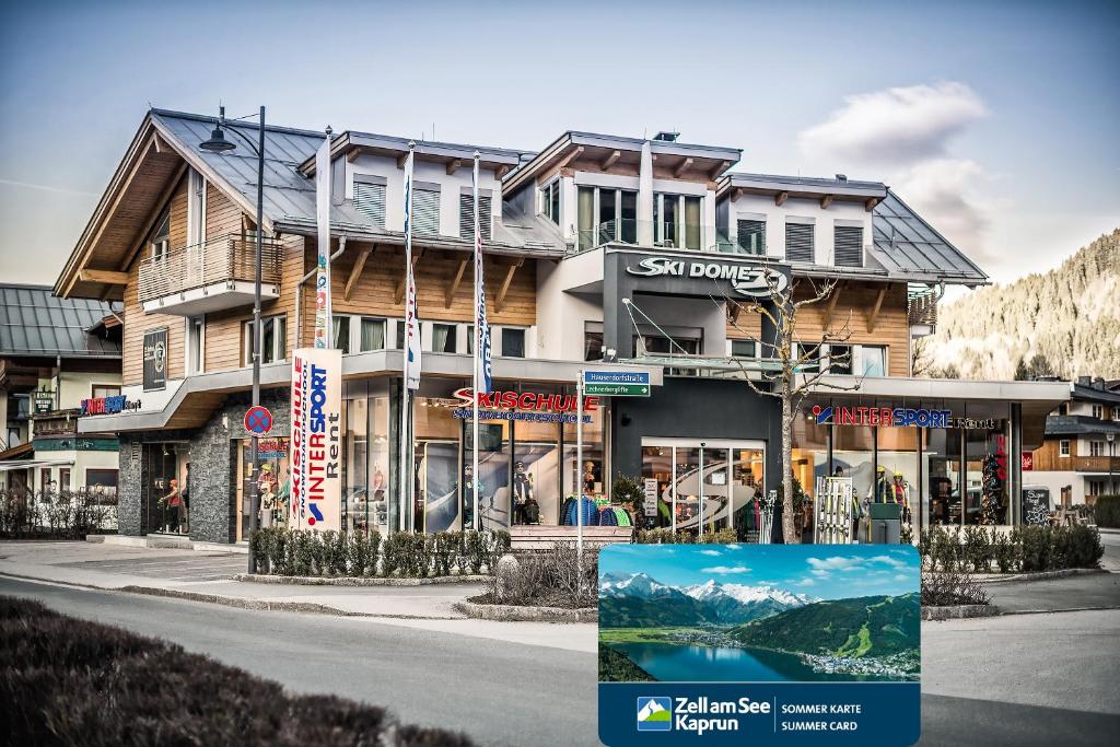 a building in the mountains with a sign in front of it at Ski Dome Apartments & Heaven Holiday Chalet in Kaprun