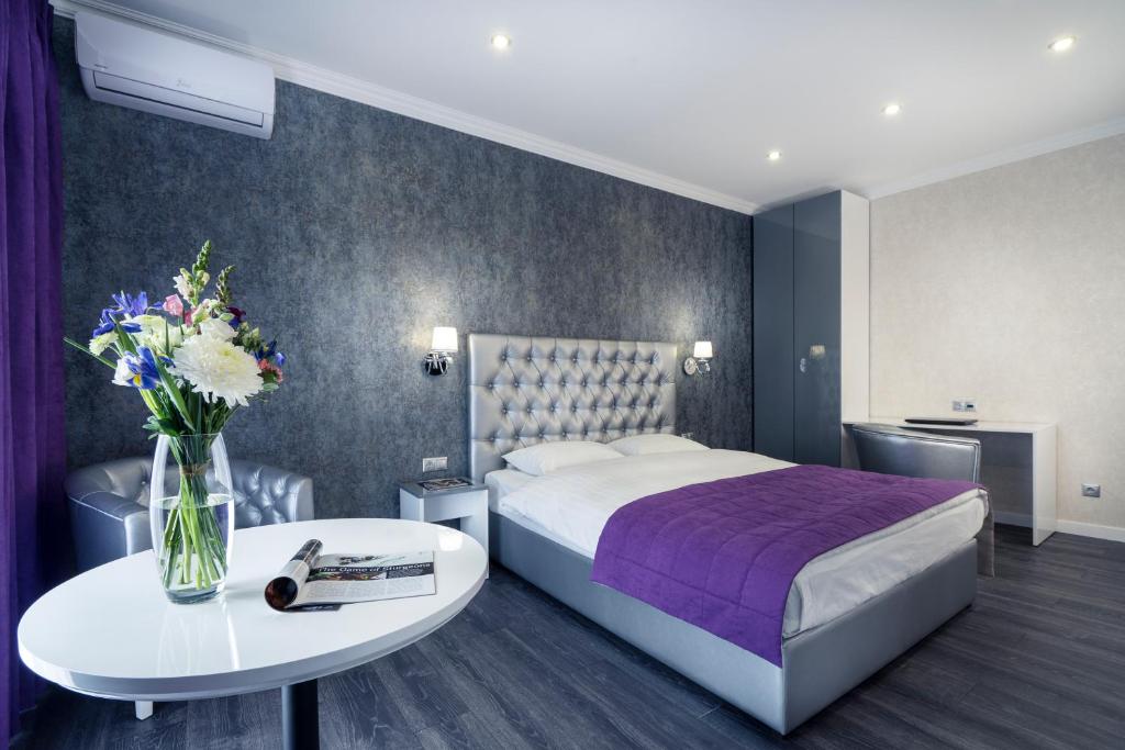ستاتيوس أبارتمنتس في كييف: غرفة في الفندق بها سرير وطاولة بها زهور