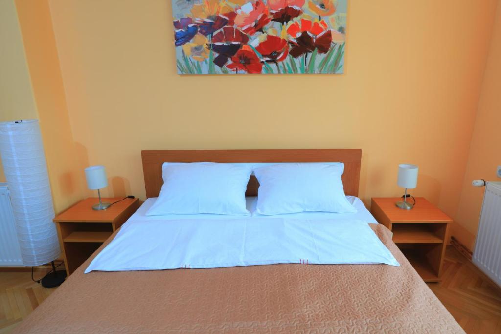 a bedroom with a bed with two nightstands and a painting at Apartman Tina Sokobanja in Soko Banja