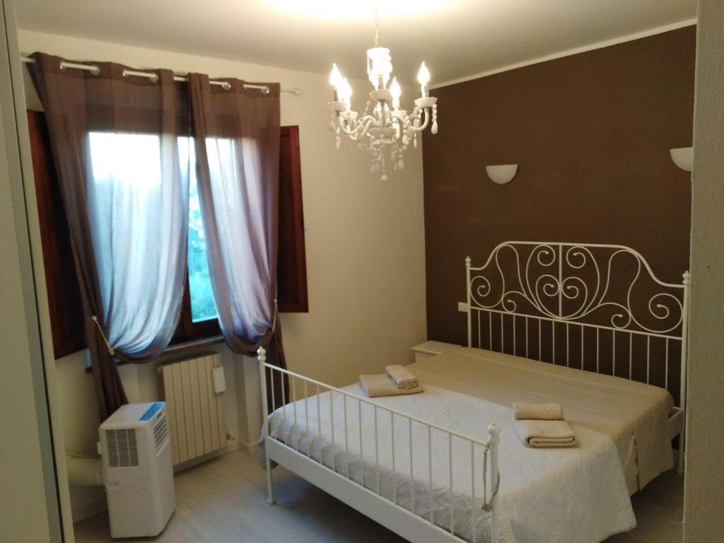 - une chambre avec un lit blanc et un lustre dans l'établissement Il glicine, à Sienne