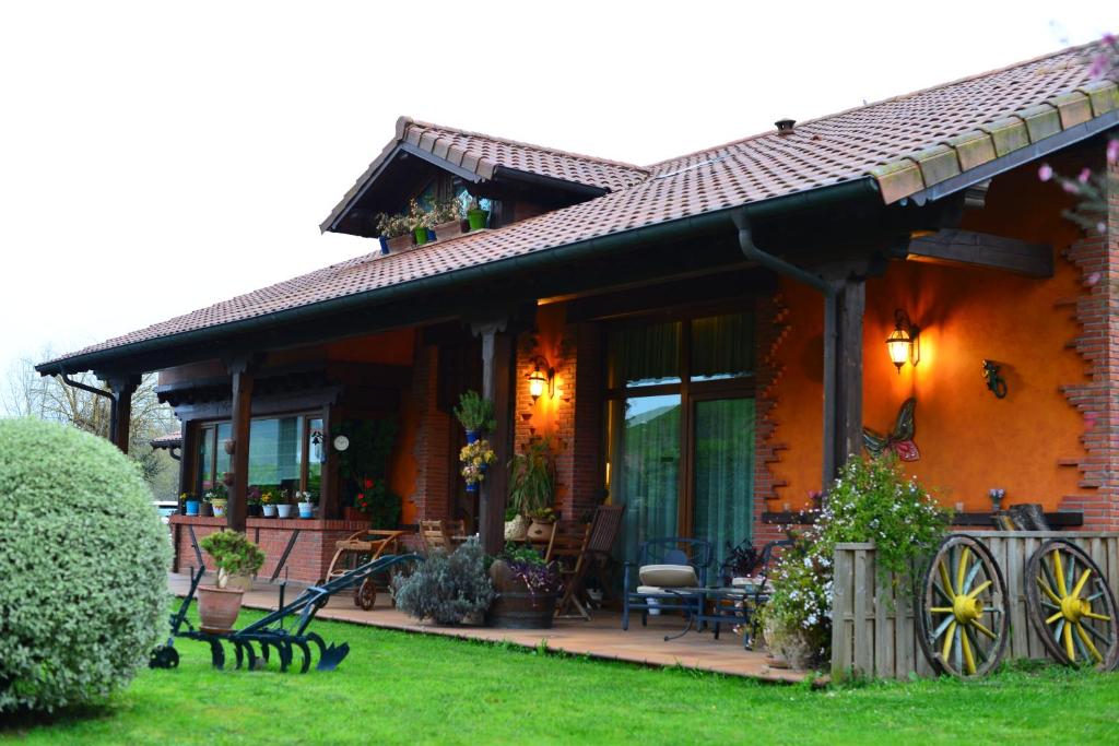 ein orangefarbenes Haus mit einer Veranda und einer Terrasse in der Unterkunft Alojamiento Bernabales in Pámanes