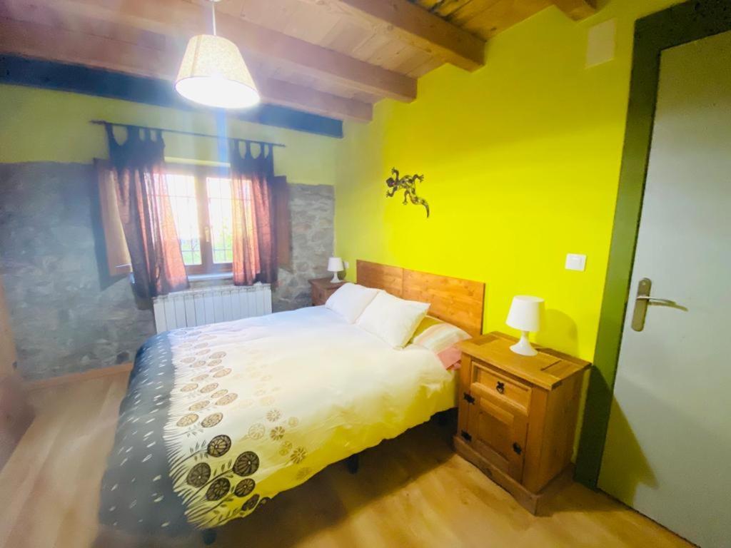 a bedroom with a bed and a yellow wall at Alojamientos Casa San Apartamentos in Besande