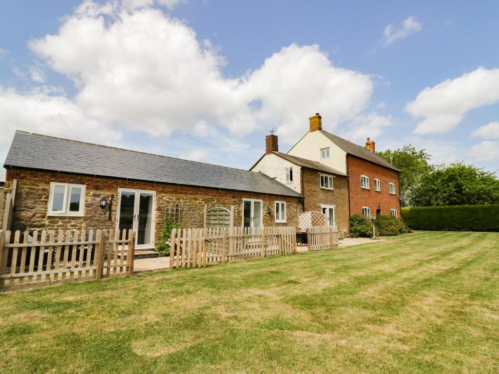 a house with a wooden fence in front of a yard at Oak Barn in Daventry