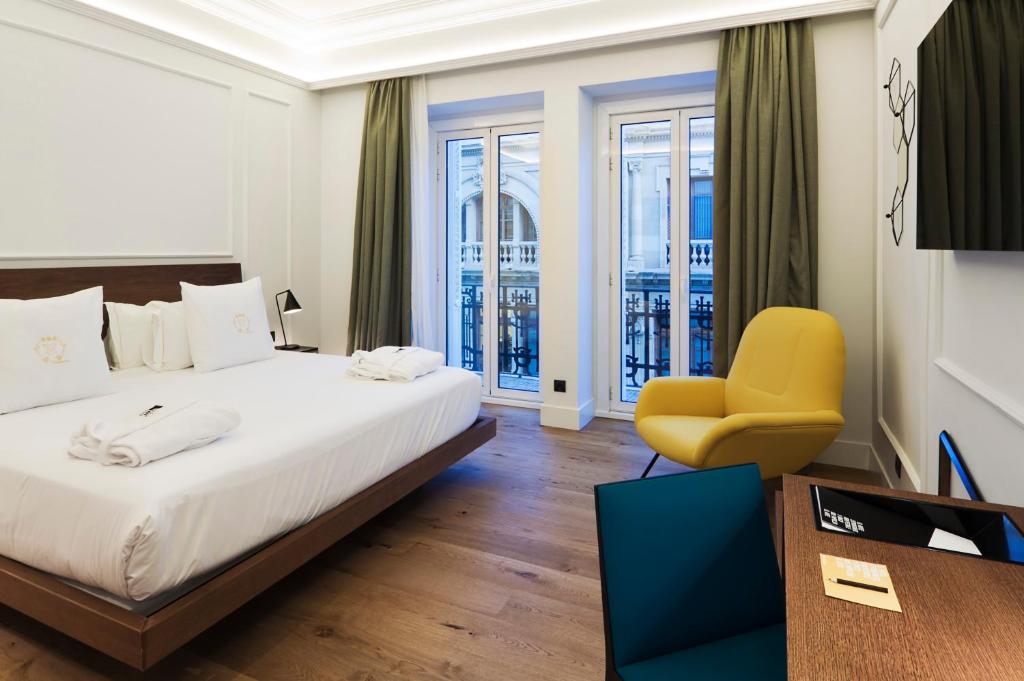 een hotelkamer met een bed en een gele stoel bij One Shot Reina Victoria in Valencia