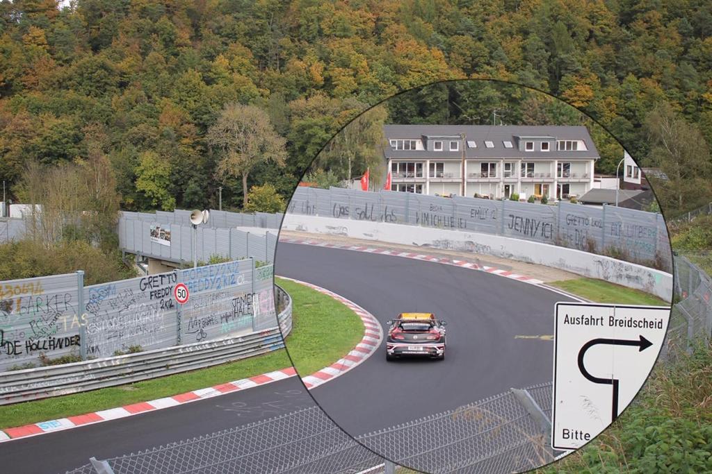 un coche conduciendo alrededor de una curva en una pista de carreras en NringRooms Exit-Breidscheid, en Adenau