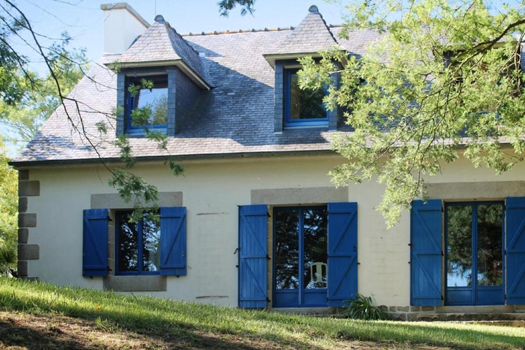 ein altes weißes Haus mit blauen Fensterläden in der Unterkunft Maison de 4 chambres avec jardin amenage a Plougrescant a 2 km de la plage in Plouguiel