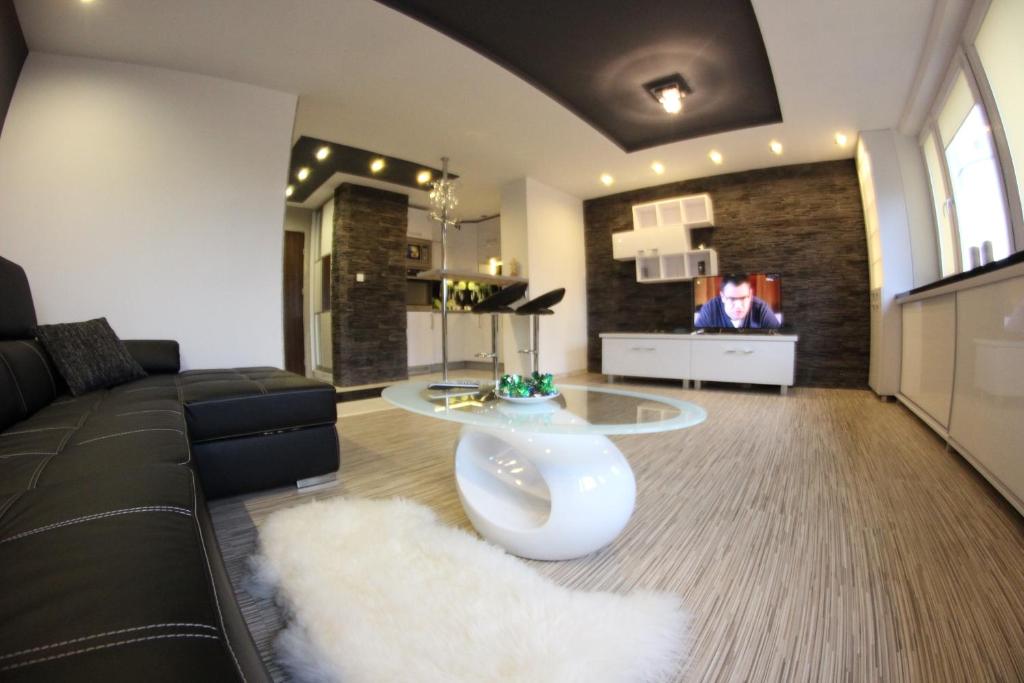 a living room with a black couch and a white rug at Black & White Komfortowe Apartamenty 2 km od Centrum in Racibórz