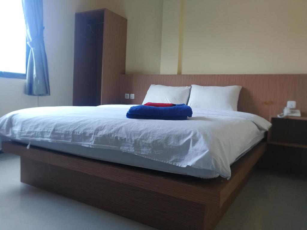 a bed with a blue pillow on top of it at Hotel Mayang Sari 1 in Jambi