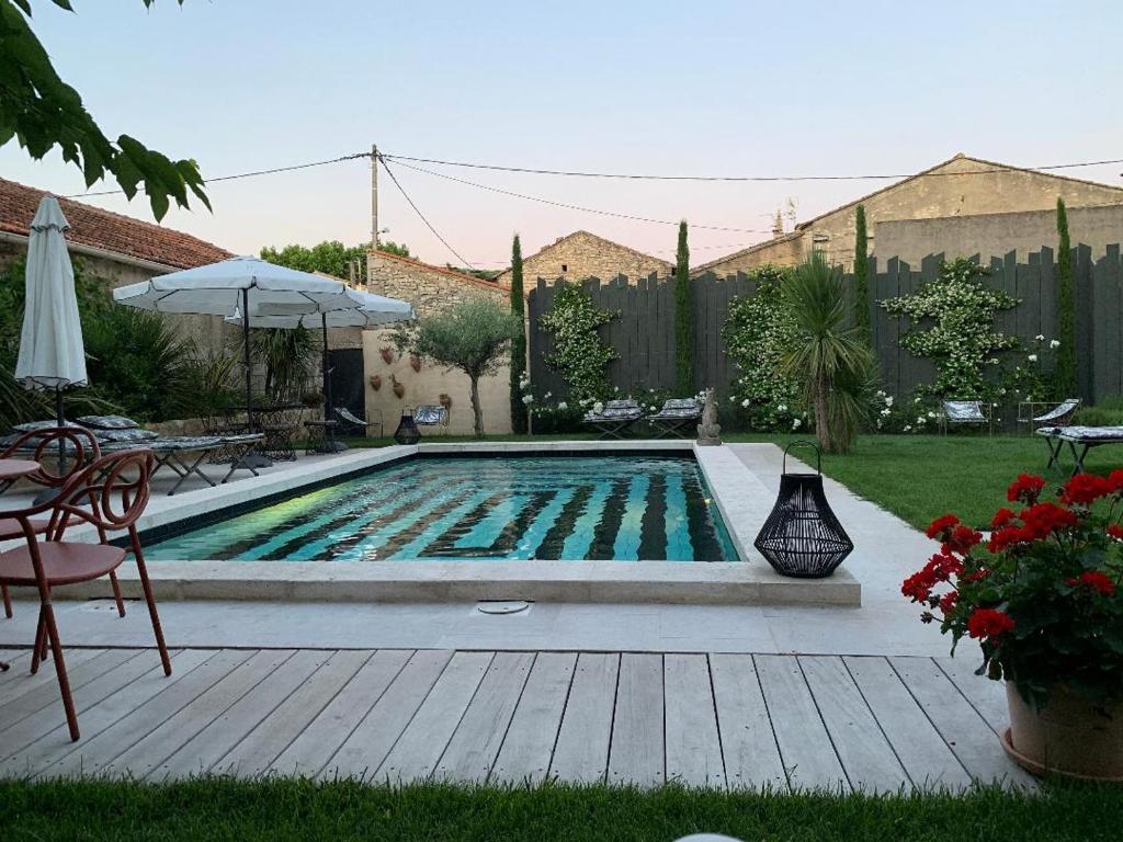 een zwembad in een tuin met een tafel en een parasol bij Le petit hotel in Saint-Rémy-de-Provence