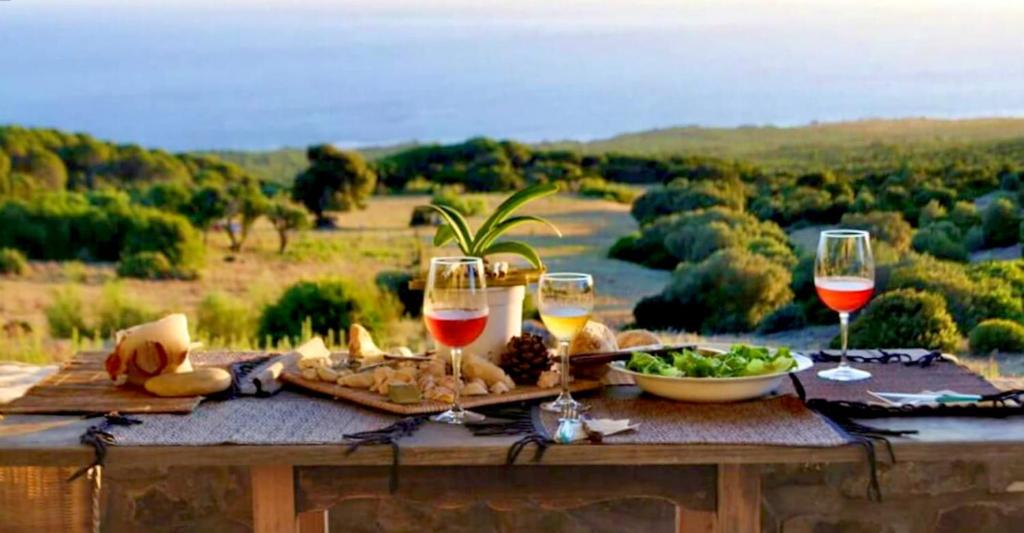 una mesa de picnic con copas de vino y comida. en Charming house with sea and mountain views in El Chaparral, en El Chaparral