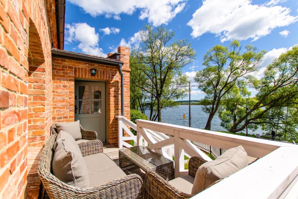 balkon z wiklinowymi krzesłami i widokiem na wodę w obiekcie DOMKI APARTAMENTOWE CHMIELÓWKA w Chmielnie