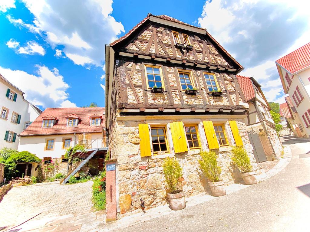 ein altes Steingebäude mit gelben Fensterläden auf einer Straße in der Unterkunft LANDHOTEL 1707 by Landgasthof Zickler in Gleisweiler