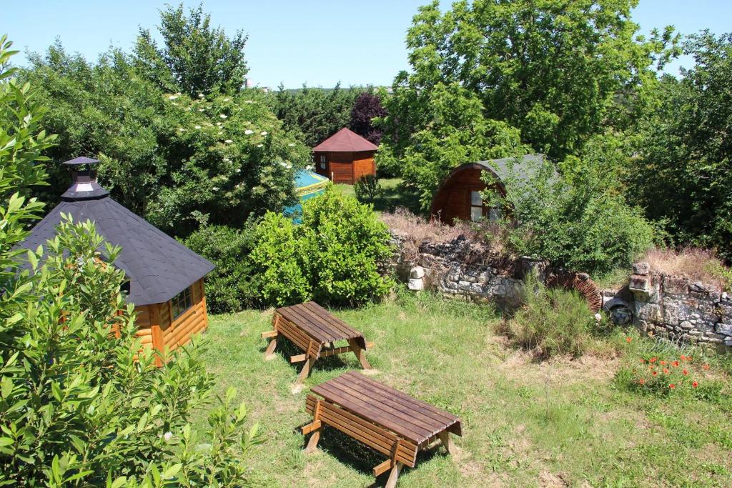 a group of benches in a garden with a building at La Longère du Parc in Noyers-sur-Cher