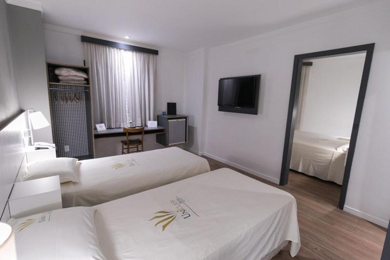 a hotel room with two beds and a flat screen tv at Uniclass Hotel Pinheiros in Sao Paulo