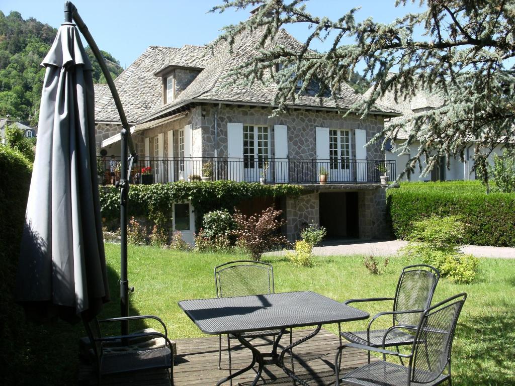 une table, des chaises et un parasol en face d'une maison dans l'établissement Studio Vic, à Vic-sur-Cère