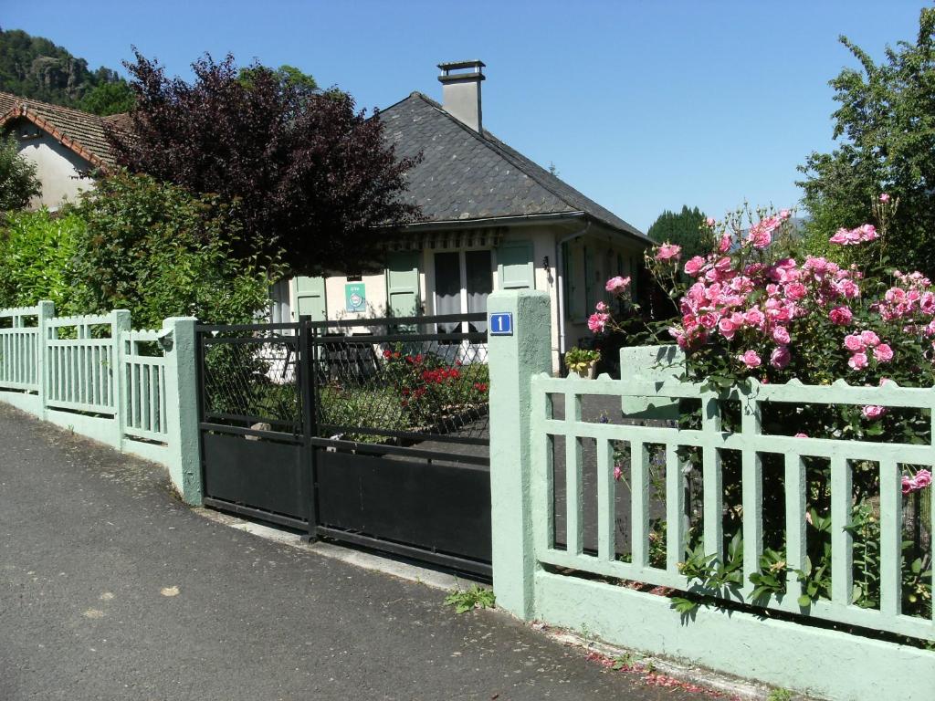 une clôture blanche devant une maison fleurie dans l'établissement Chez Léontine, à Vic-sur-Cère