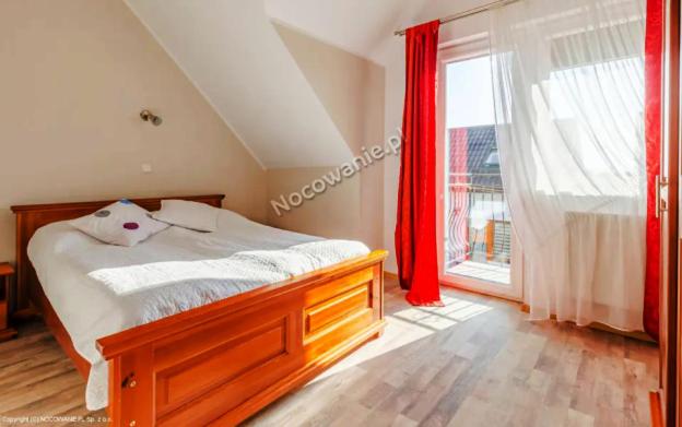 a bedroom with a bed and a large window at Dom Wczasowy MONIKA in Jastarnia