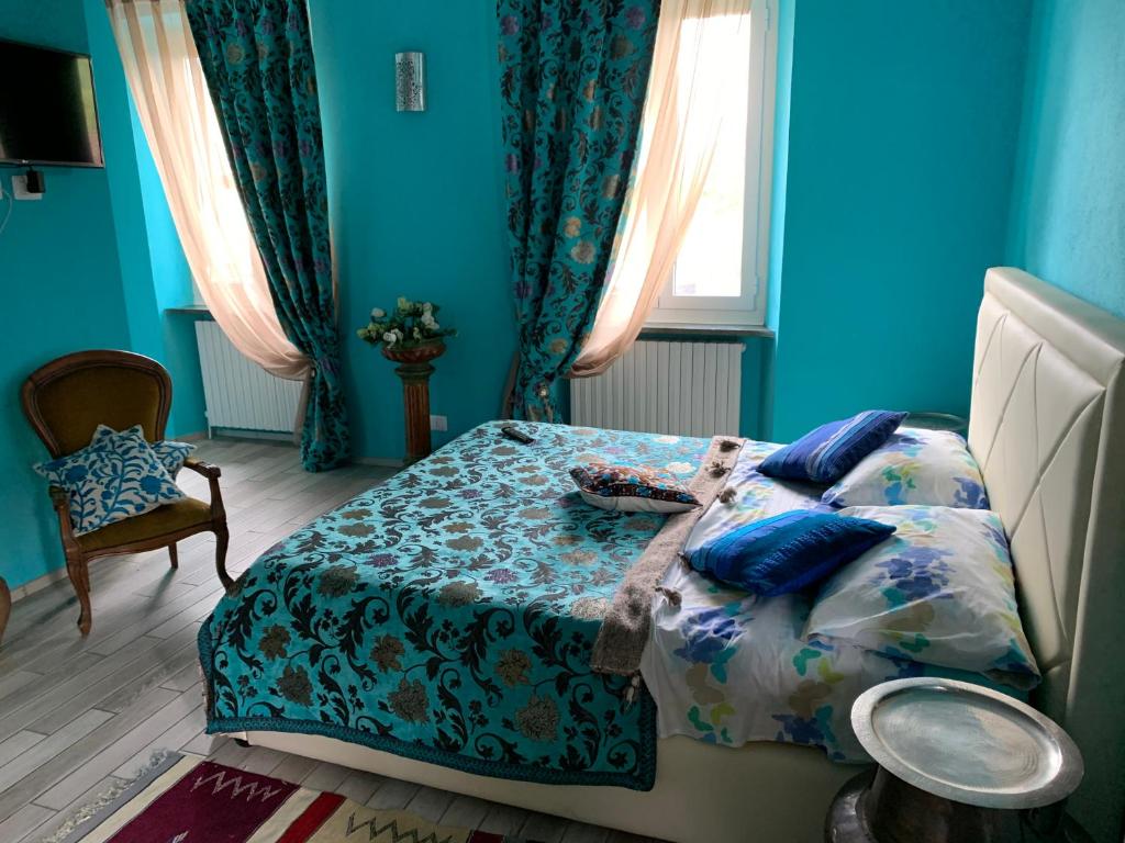 Dormitorio azul con cama y ventana en Alla corte dei Caretto, en Neive