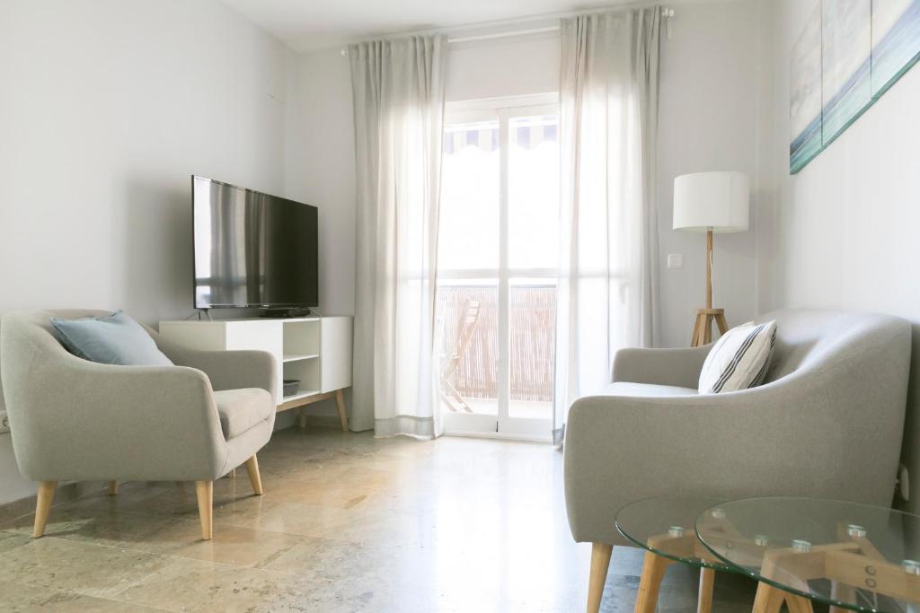 sala de estar con 2 sillas y TV en Apartamento Málaga Velázquez, en Málaga