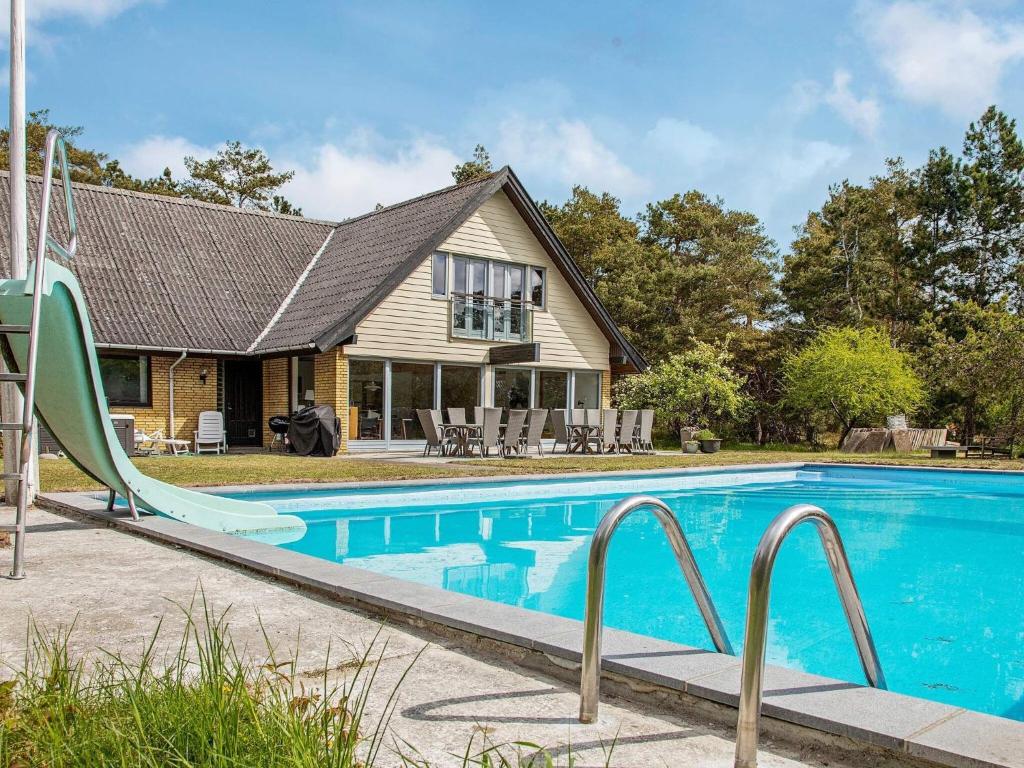 a swimming pool with a slide in front of a house at 14 person holiday home in Sj llands Odde in Tjørneholm