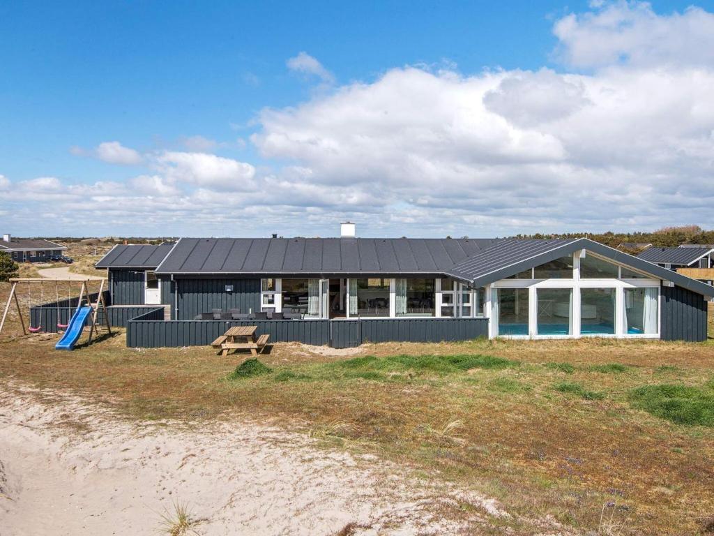 uma casa com um telhado preto numa praia em 10 person holiday home in Fan em Sønderho