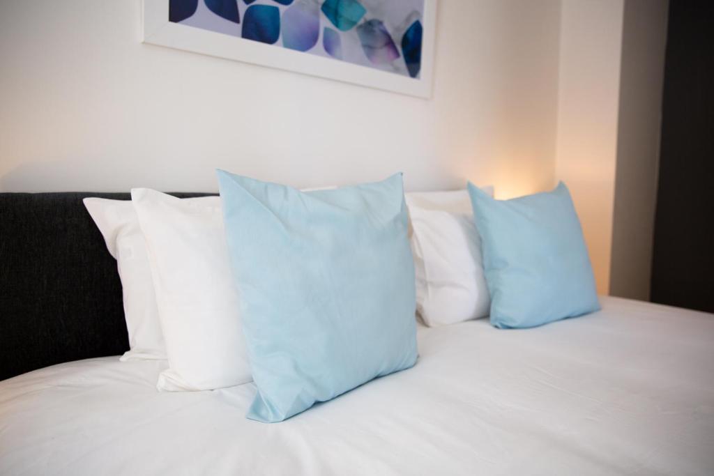 2 almohadas azules sentadas en una cama con almohadas blancas en Velvet 1-bedroom apartment, Clockhouse, Hoddesdon, en Hoddesdon