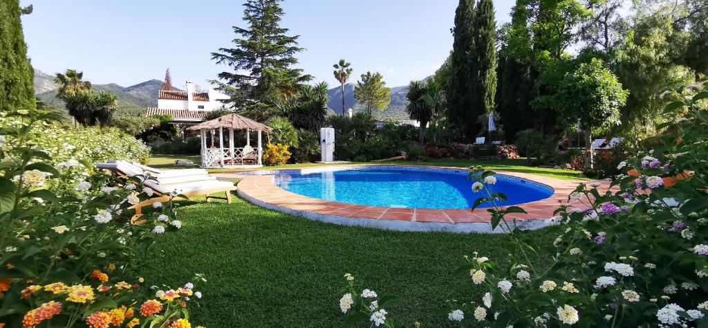 a swimming pool in a yard with a bench and flowers at Roca Verde, Boutique Bed & Breakfast in Alhaurín de la Torre