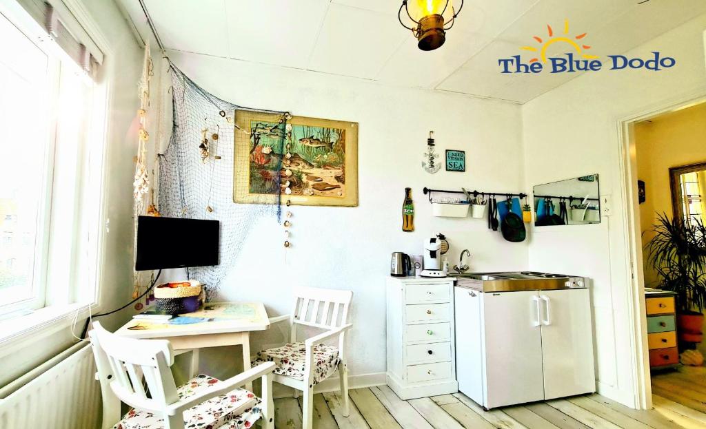 Il comprend une cuisine équipée d'un réfrigérateur et d'un bureau avec deux chaises. dans l'établissement The Blue Dodo, à Zandvoort