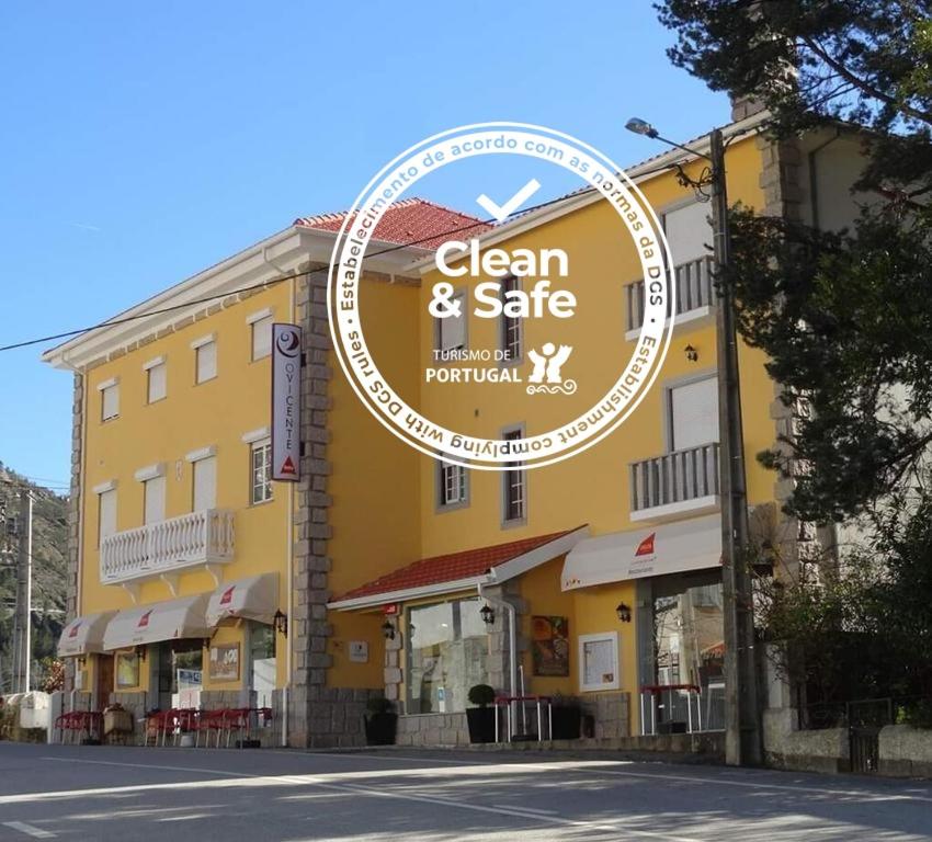 een geel gebouw met een bord dat schoon en veilig is bij O Vicente in Loriga