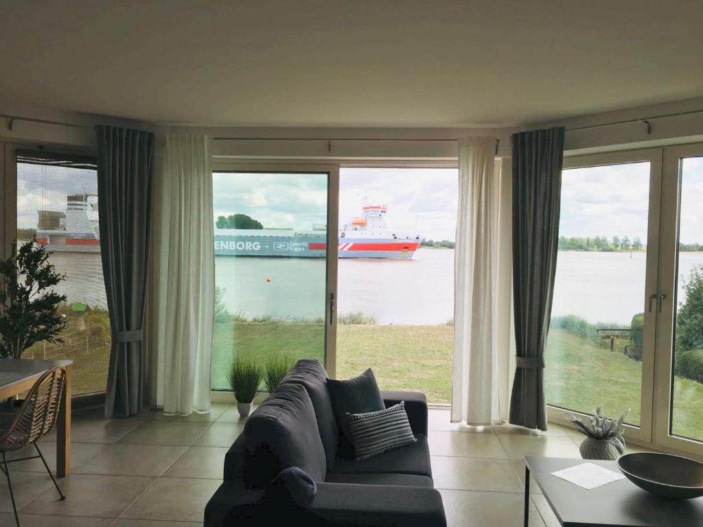 a living room with a large window with a ship in the water at NAUTIK STRANDAPARTMENTS Luxuswohnung Atlantik in Brake
