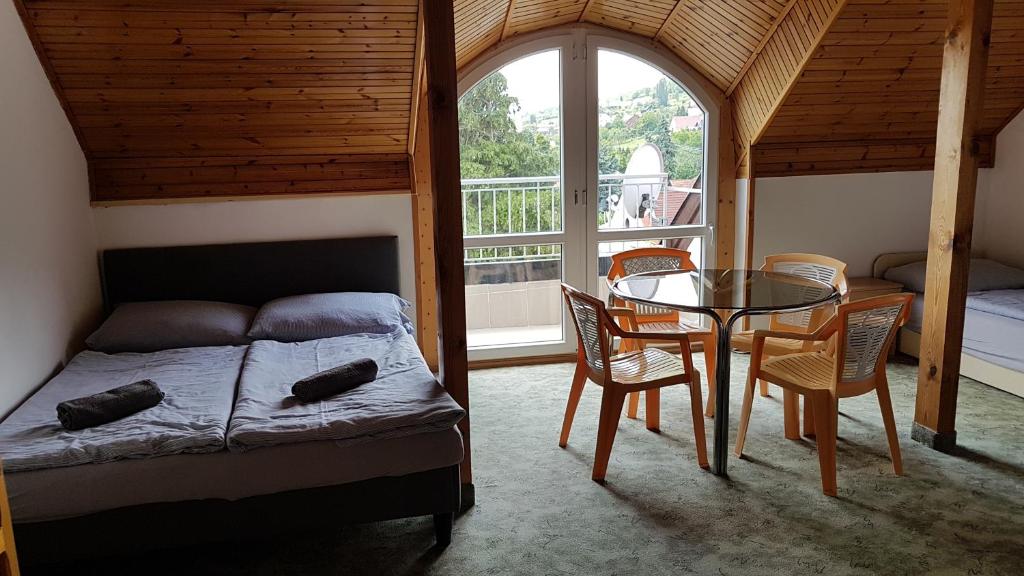 een slaapkamer met een bed en een tafel en stoelen bij Szatmári Vendégház in Badacsonytomaj